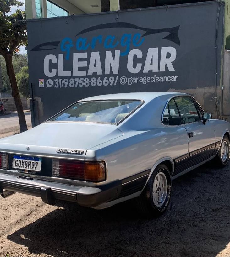 Opala Comodoro azul claro visto de trás em frente ao letreiro CLEAN CAR