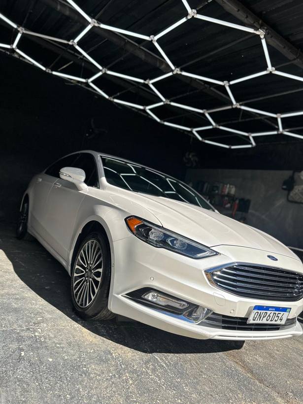 Ford Fusion branco polido sob as luminárias hexagonais