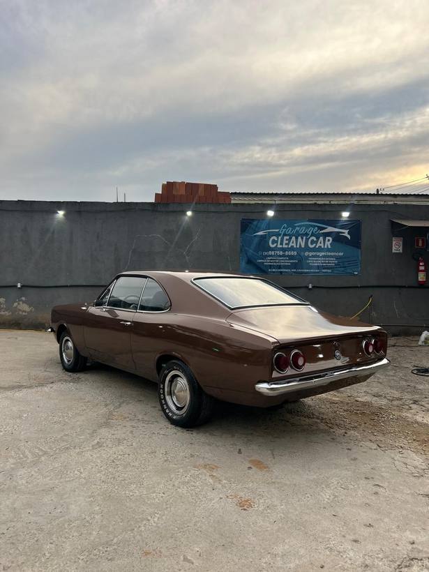 Opala coupé caramelo ao pôr do sol com a faixa da Garage CleanCar ao fundo